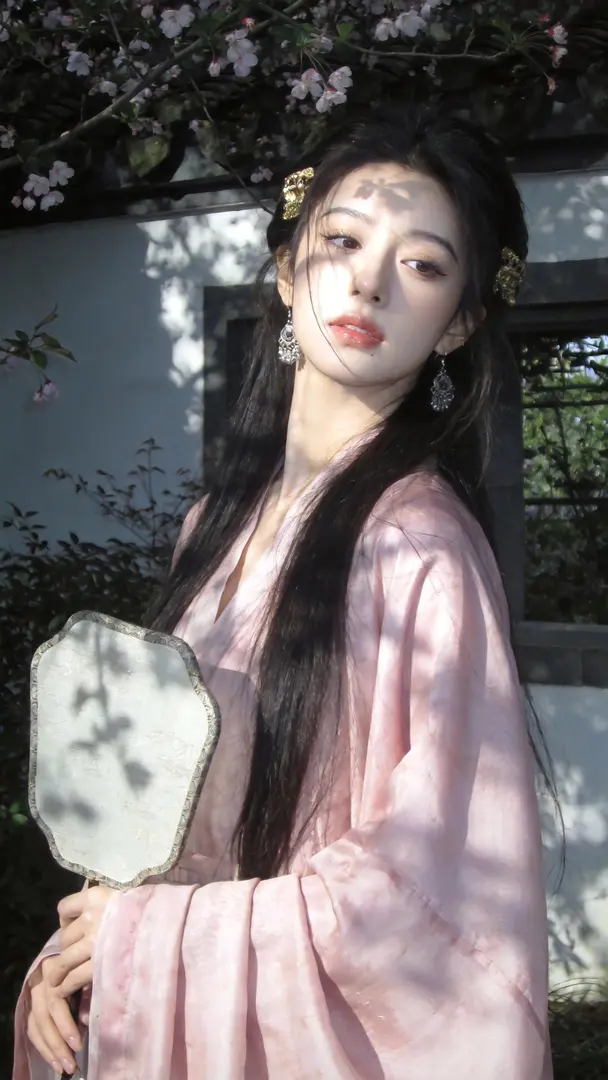 「光影治愈系写真,主打“温柔静谧的文艺氛围”。美人,藕粉真丝面料,广袖羽衣,青铜发饰,发饰,两鬓有金色发饰,细节丰富,一把团扇。 庭院里,海棠树下,利用窗外植物投影的斑驳光影做天然装饰,让树影与光斑在墙面、裙身交织,营造出"花谢花飞飞满天…