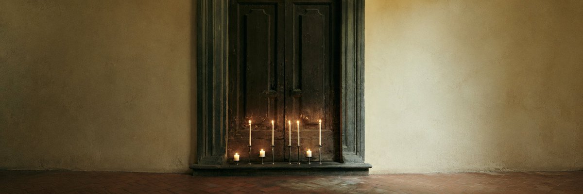 Create a cinematic ultra-wide 3:1 photorealistic interior scene: a quiet old European room with a dark, tall, closed do…