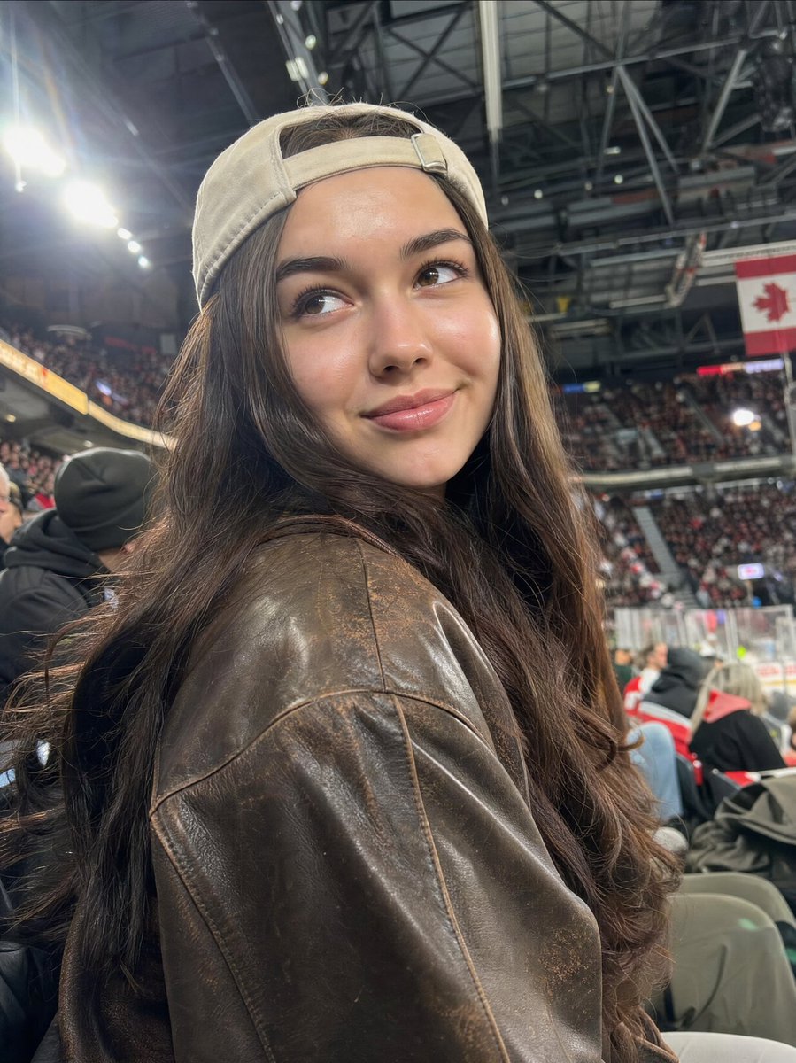 A high-quality, realistic candid photo of a beautiful young woman in a {argument name="setting" default="crowded sports…