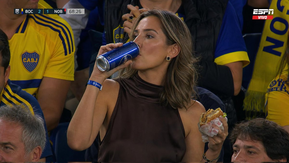 Ultra-realistic sports broadcast still of a glamorous {argument name="subject" default="woman sitting in a packed footb…