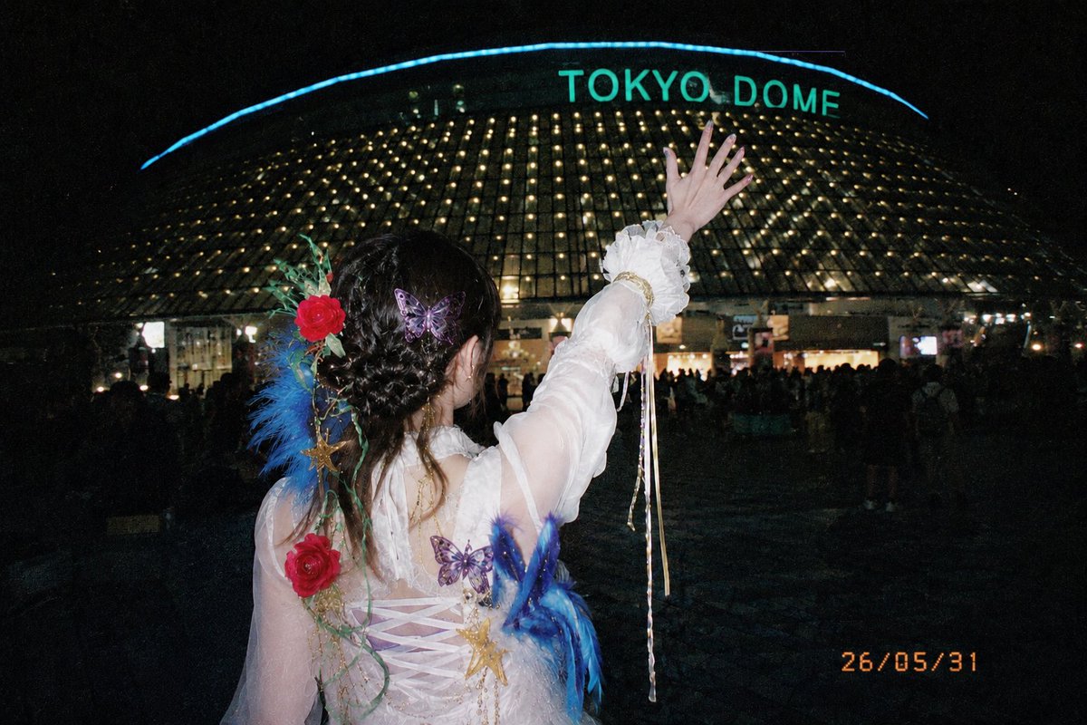 A {argument name="location" default="night view in front of Tokyo Dome"}. With the Tokyo Dome in the background, a woma…