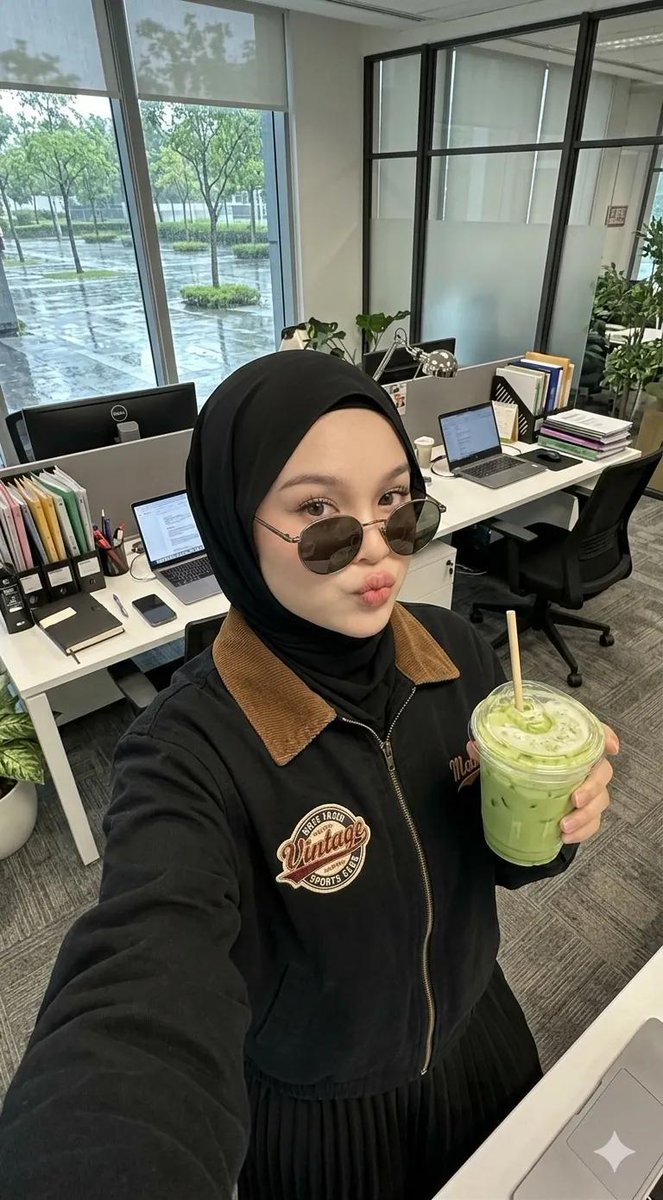 A high-angle selfie of a {argument name="subject" default="young woman wearing a black hijab"}, posing casually inside …